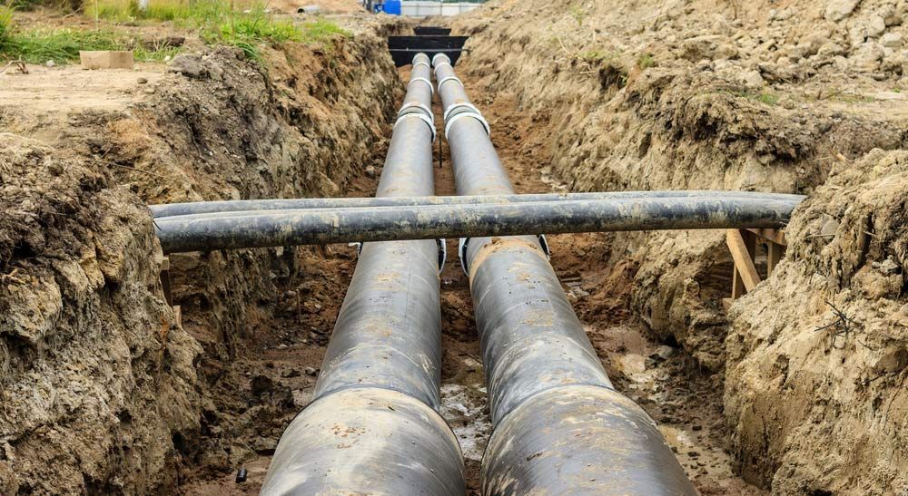 Two Pipes Are Being Installed In A Trench In The Dirt — Blackpoly Pipelines in Mount Isa, QLD