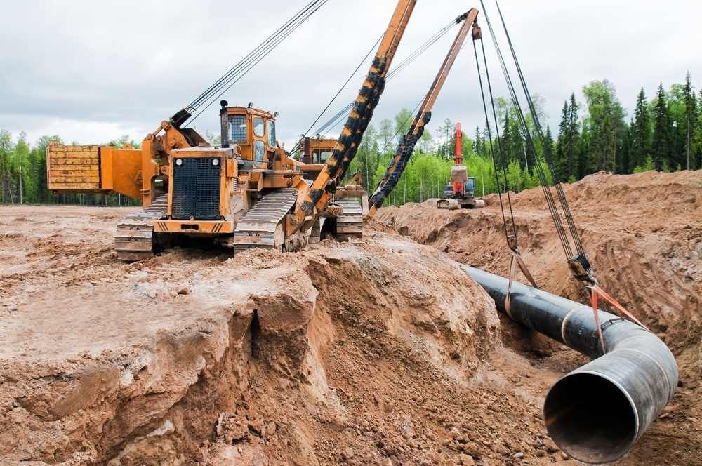 A Bulldozer Is Lifting A Pipe In The Dirt — Blackpoly Pipelines in Gilgandra, NSW