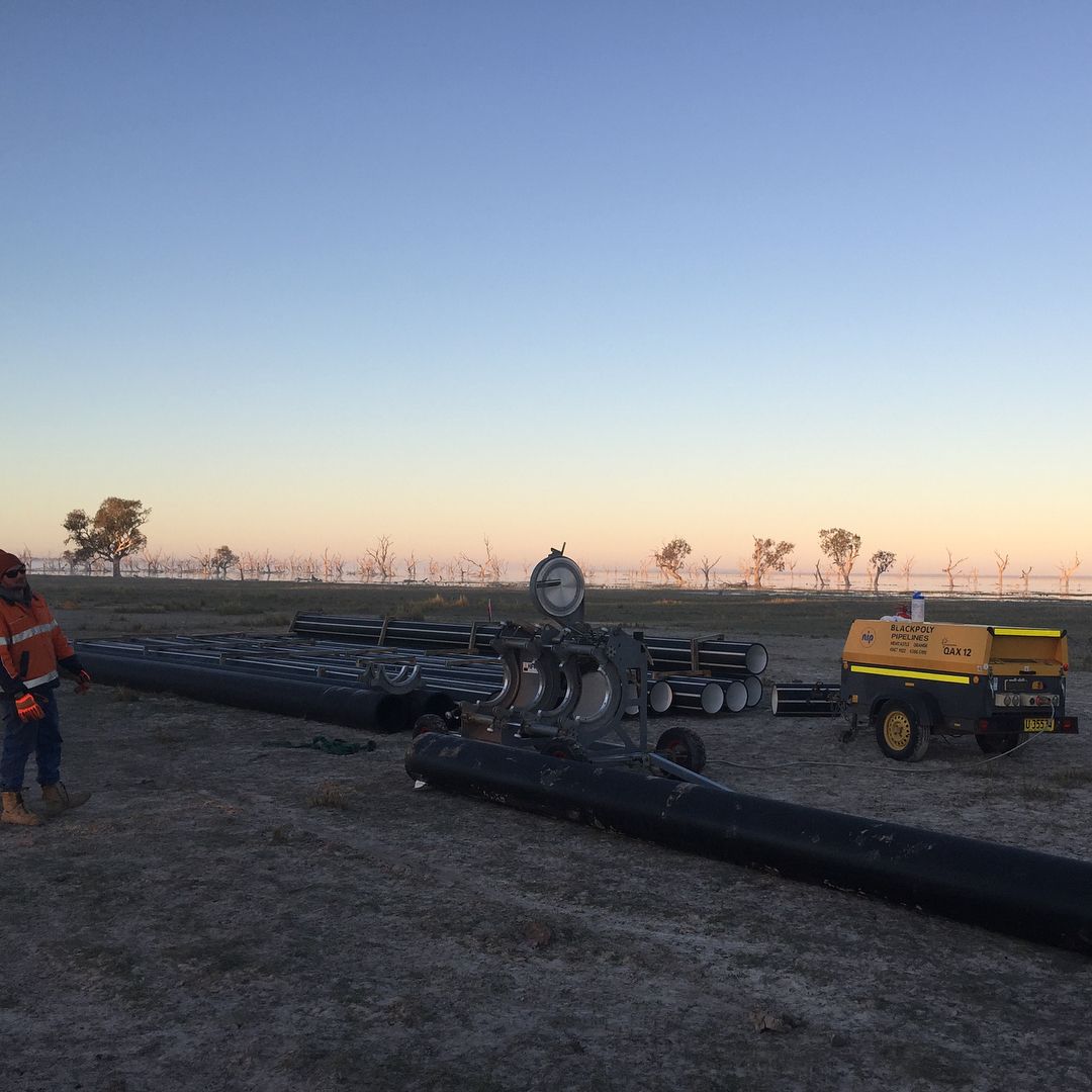 A Man Is Standing Next To A Large Pipe In A Field — Blackpoly Pipelines in Orange, NSW
