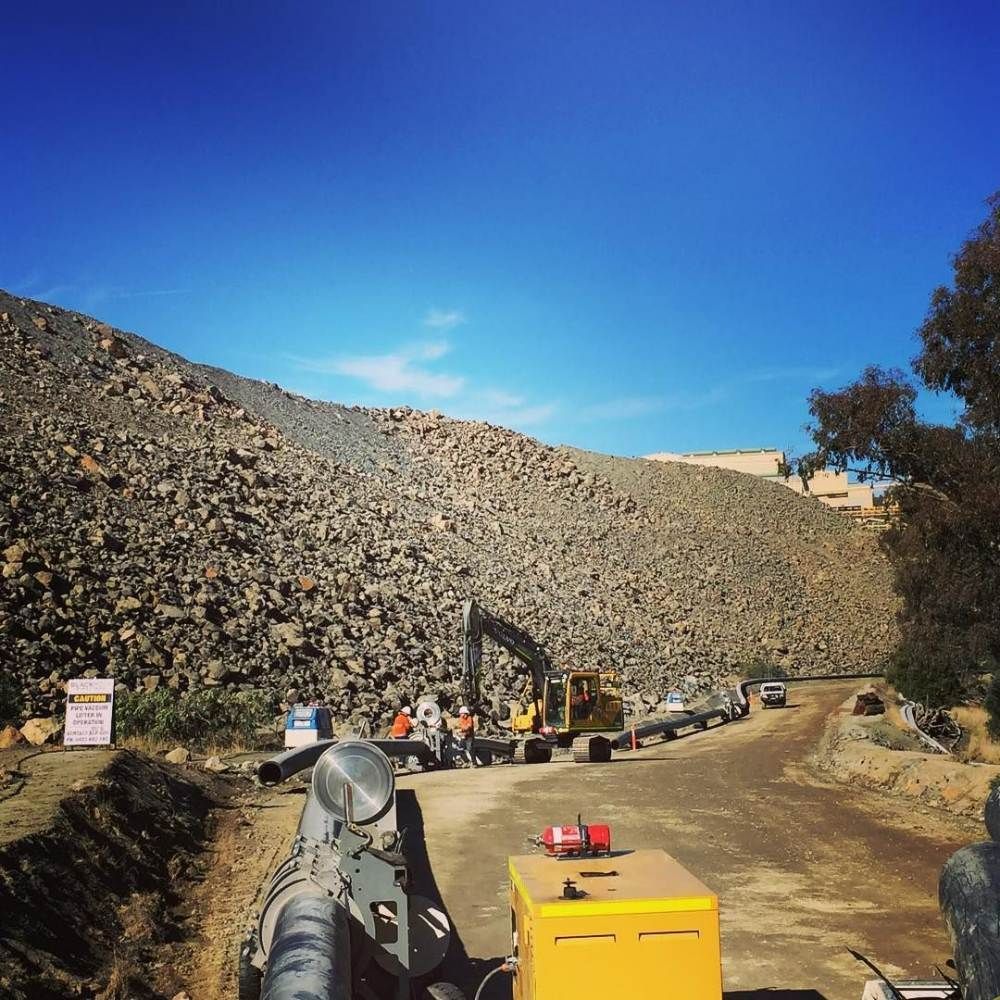 A Row Of Construction Vehicles Are Parked On The Side Of A Dirt Road — Blackpoly Pipelines in Orange, NSW