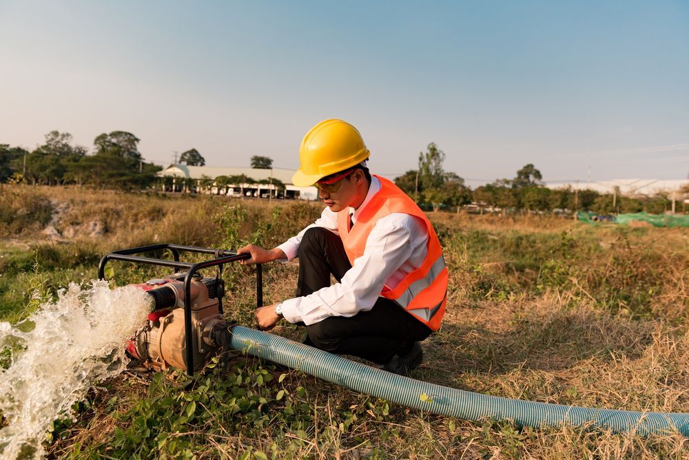 A Man Is Working On A Water Pump In A Field — Blackpoly Pipelines in Mudgee, NSW