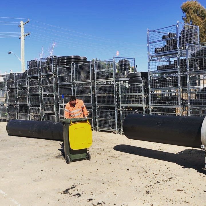 A Man Pushing A Yellow Trash Can In Front Of A Pile Of Tires — Blackpoly Pipelines in West Wyalong, NSW
