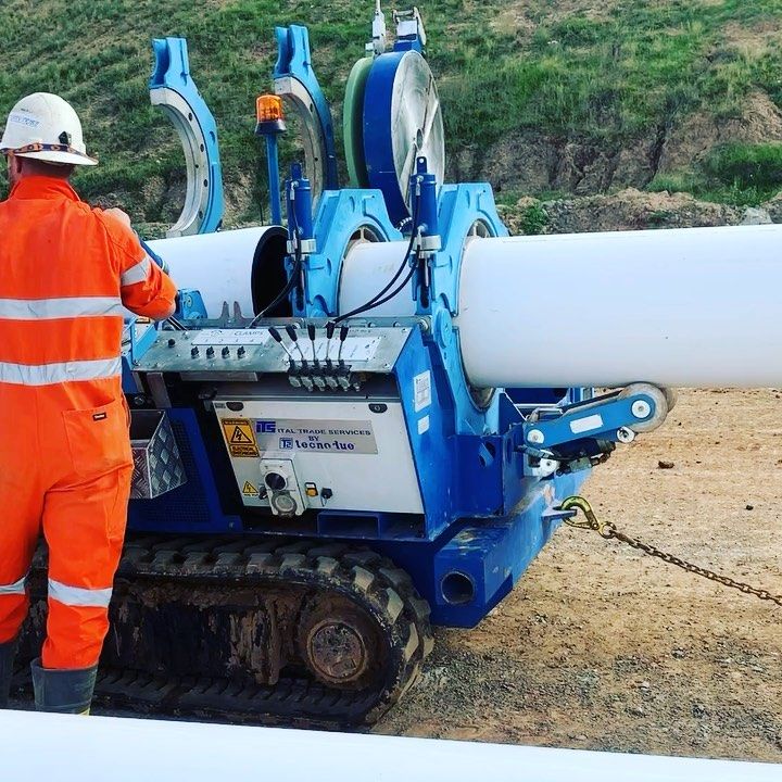 A Man In An Orange Jumpsuit Is Working On A Machine — Blackpoly Pipelines in Dubbo, NSW