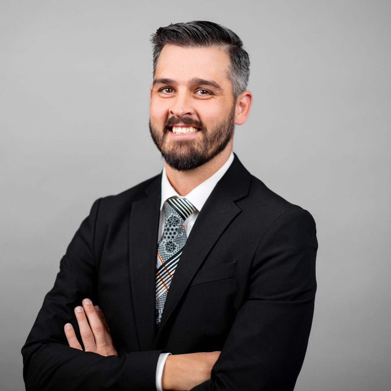 A man in a suit and tie is standing with his arms crossed.