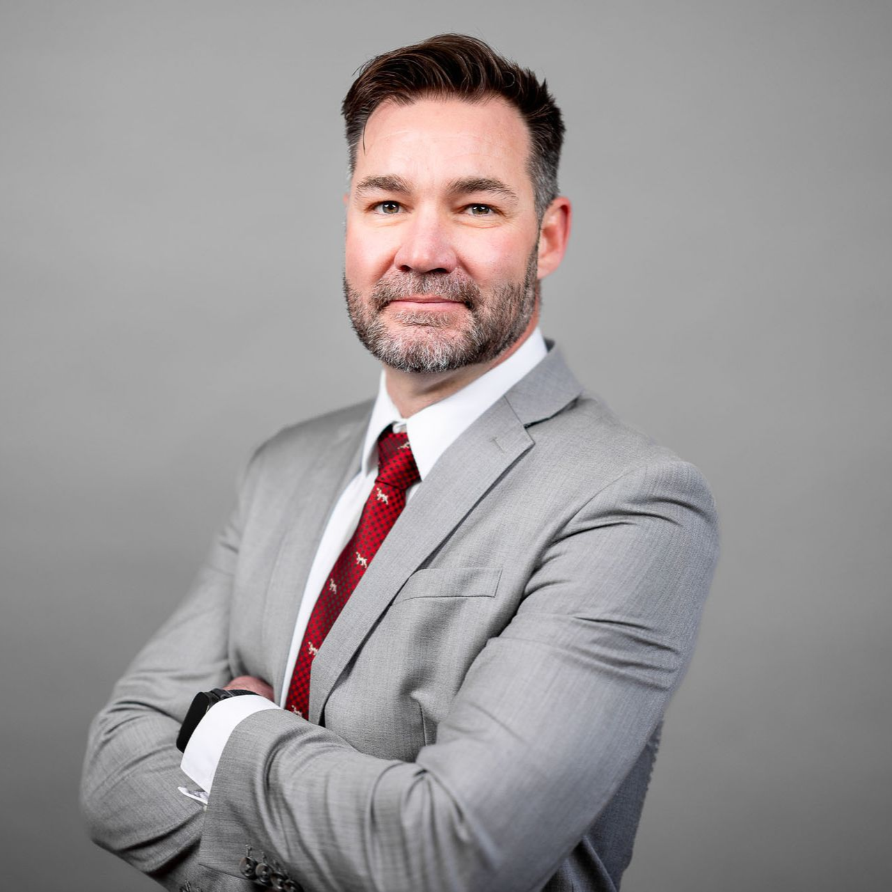 A man in a suit and tie is standing with his arms crossed.