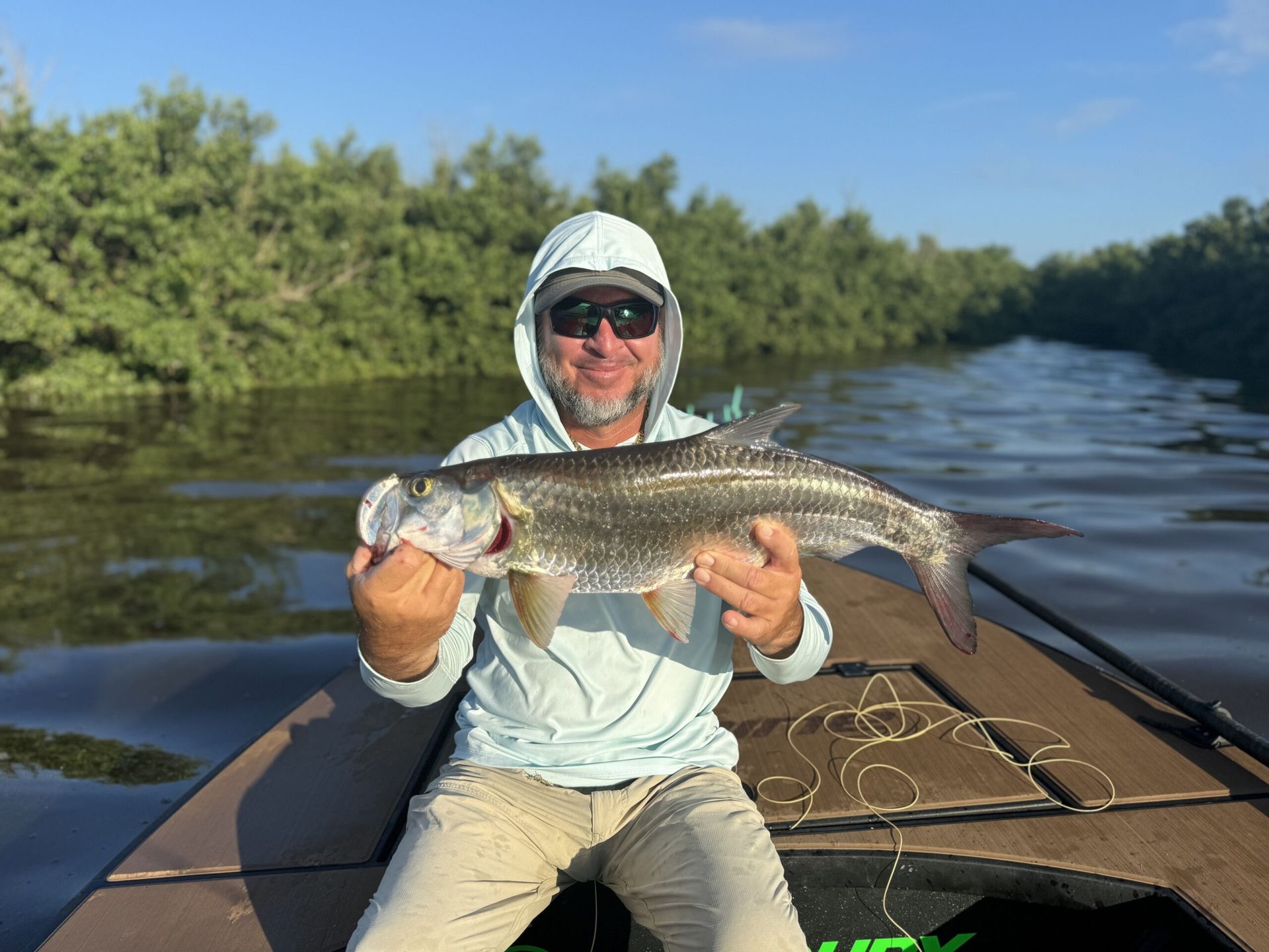 A man is sitting in a boat holding a large fish.