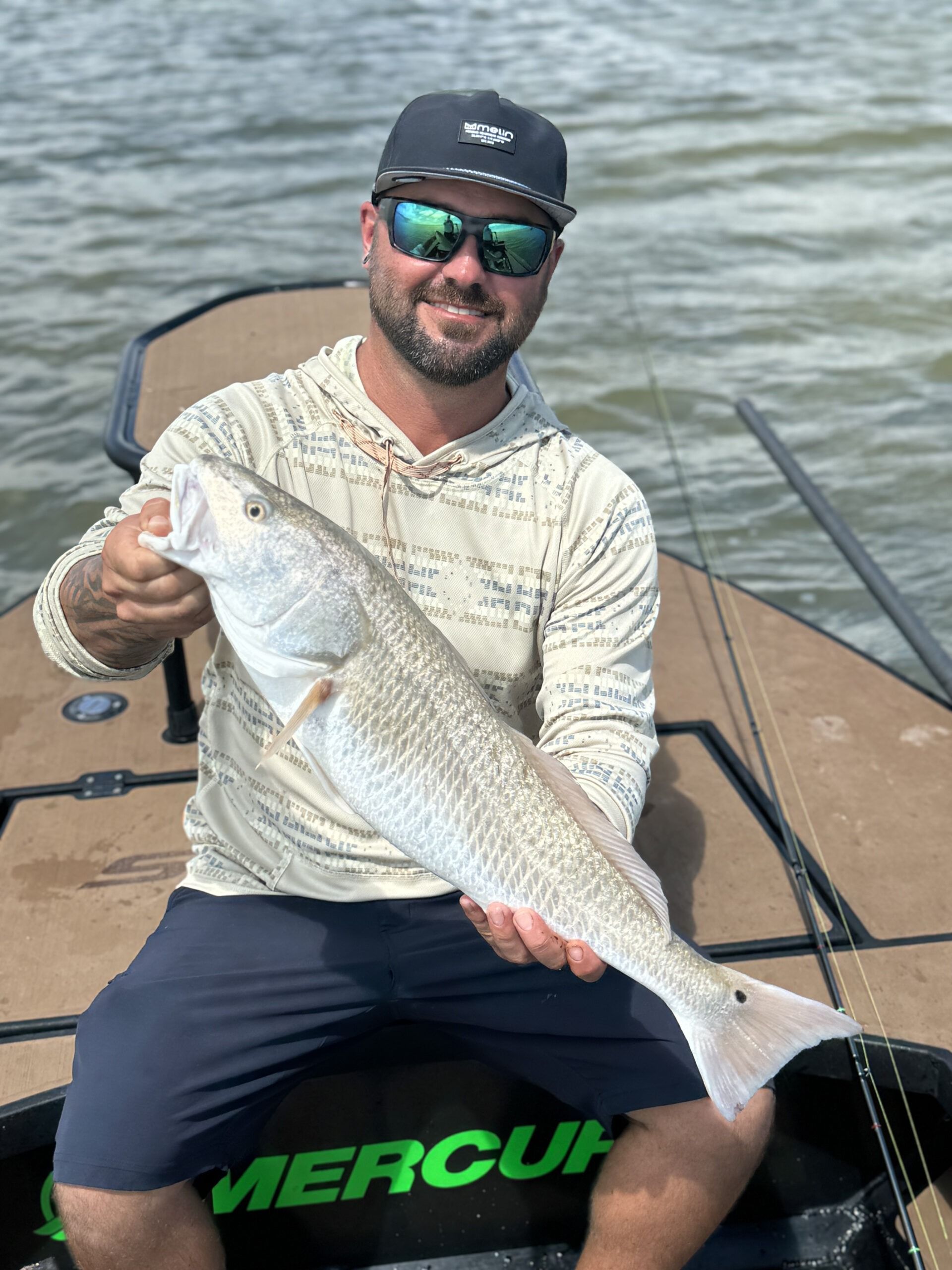 A man is sitting on a boat holding a large fish.
