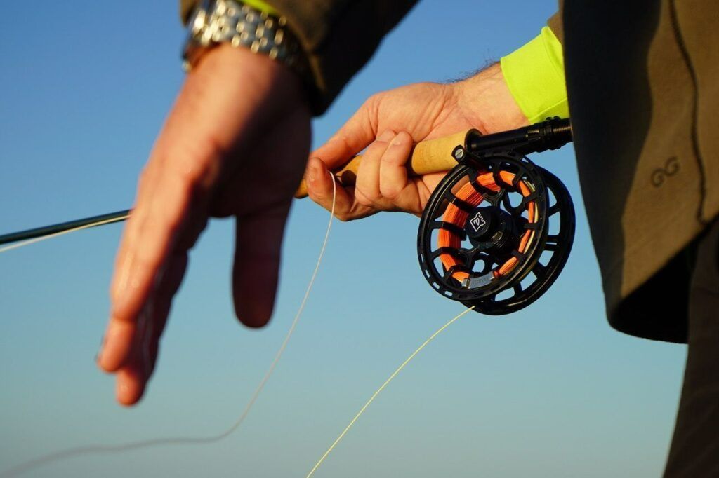 A person is holding a fly fishing rod and reel