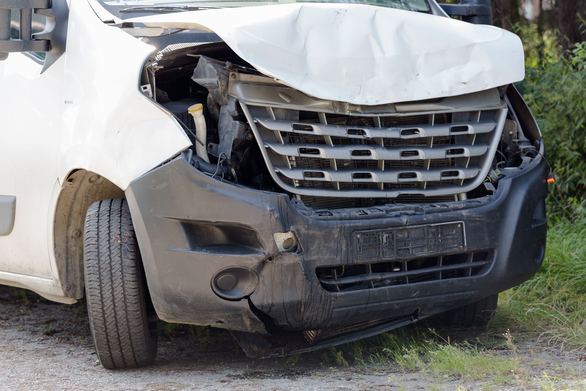 Front view of a white SUV with severe front-end crash damage and a crumpled hood.