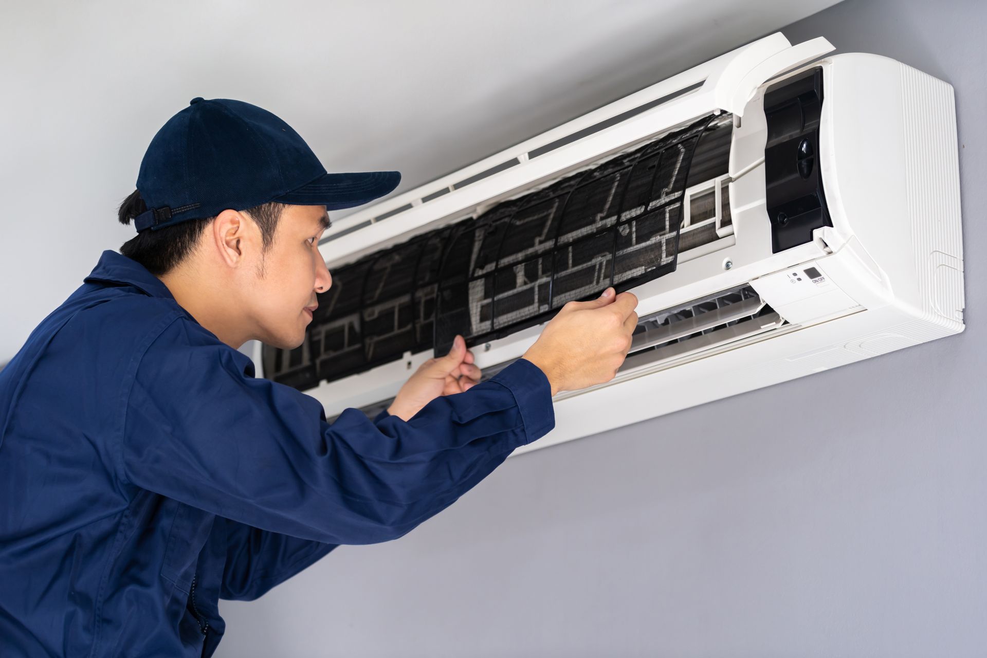 McCormick Allum fixing an air conditioner on the wall.