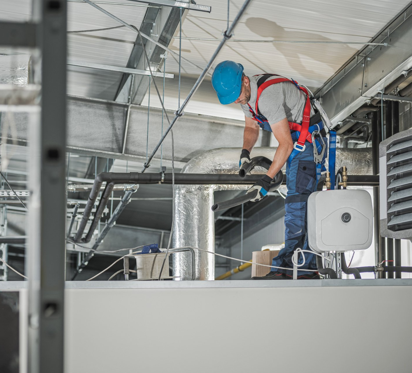 a man wearing a blue hard hat is working on a pipe and HVAC system in Springfield, MA