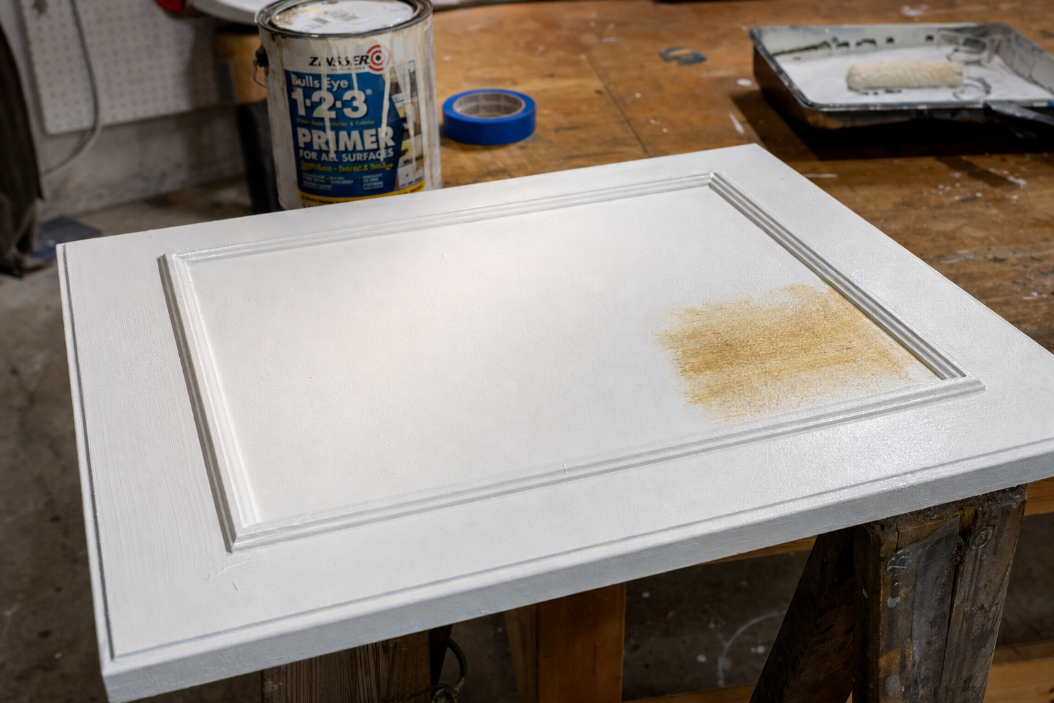 A cabinet door showing tannin bleed-through on an unprimed section next to a properly primed white 