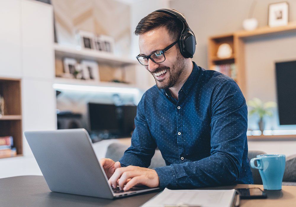 A man wearing headphones is using a laptop computer.