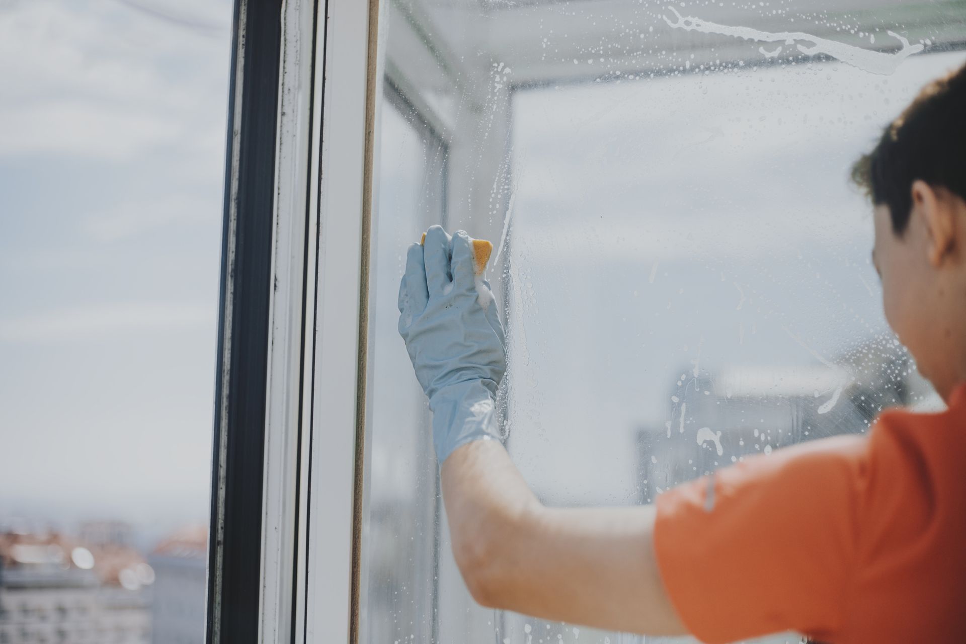 A man scrubs windows with a sponge, providing professional residential window cleaning.