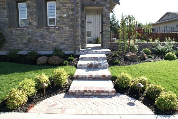 A landscape design in Davis, CA, with a brick walkway leading to the front door of a house