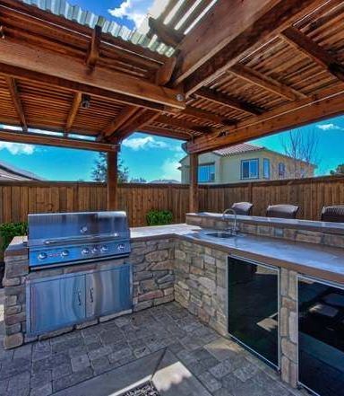 Outdoor kitchen with a grill and a wooden pergola crafted by the best landscaping company in Vacaville - Turfworks, Inc.