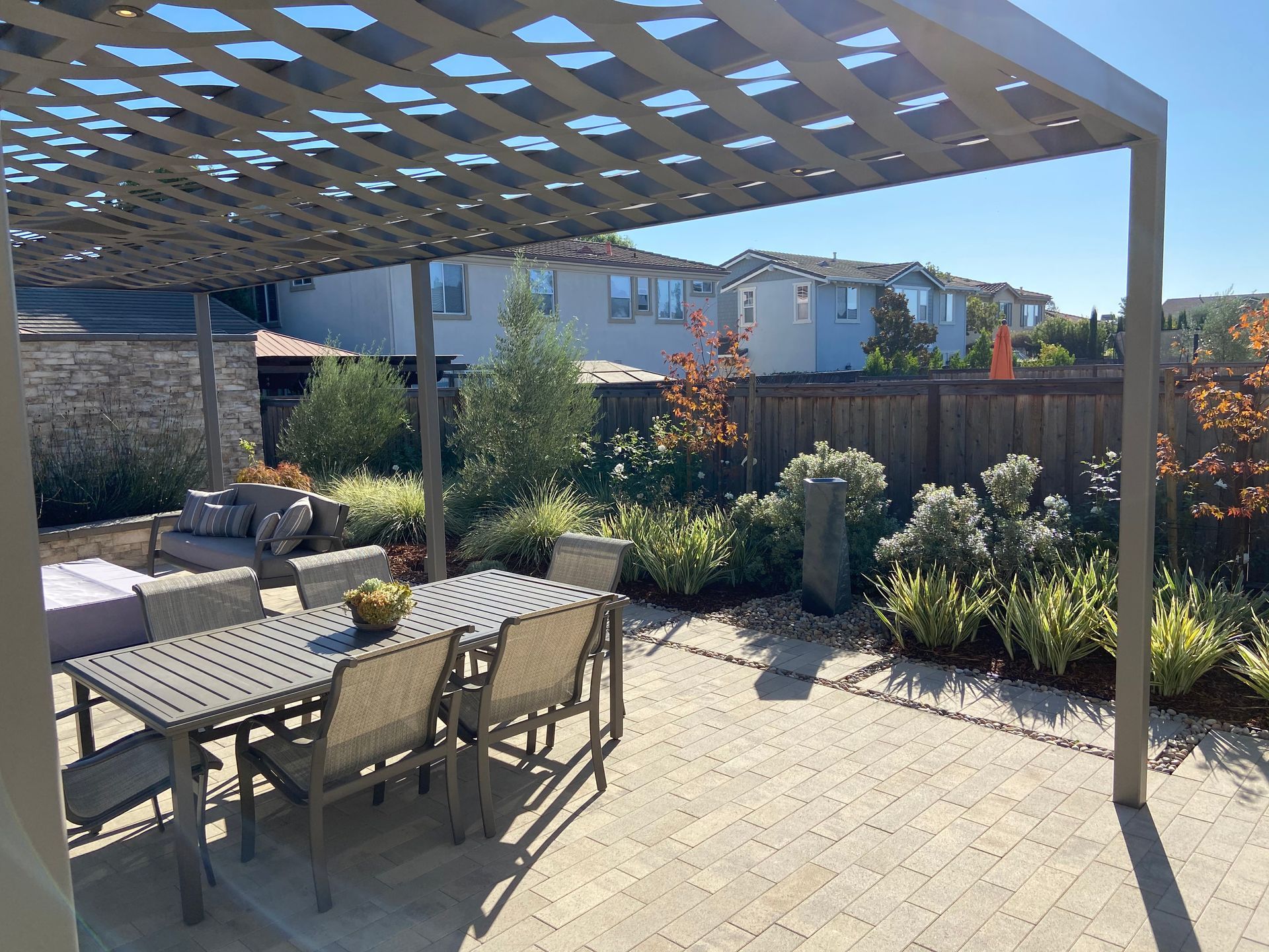 A patio under a pergola with a mini garden landscaped by Turfworks Inc., the best landscaper in Vacaville, CA.