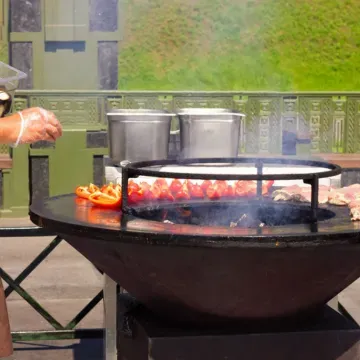 A person is cooking food in a large bowl on a grill | Landscape Design in Davis, CA
