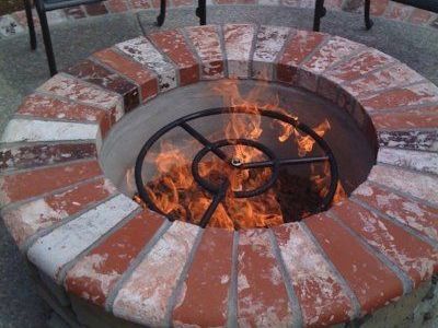 A landscape design in Davis, CA with a round brick fire pit with a metal grate in the center.