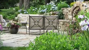 A patio with a couch and chairs in the middle of a garden. Created by Turfworks Inc. A paver contractor in Vacaville.