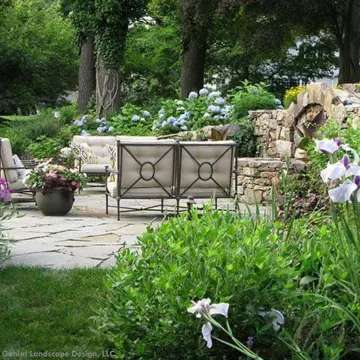 A landscape design in Davis, CA, in a garden with a couch and chairs surrounded by flowers.