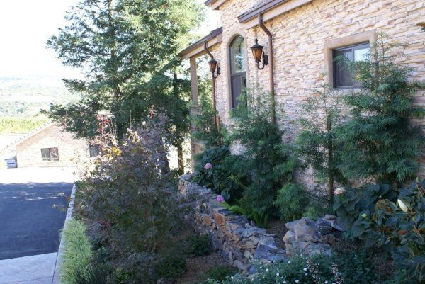 A stone building with a lot of plants and trees in front of it | Landscape Design in Davis, CA