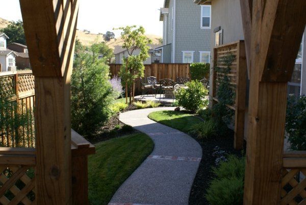 Beautiful walkway with a wooden fence and a mini garden designed by Turfworks, Inc., the best landscape company in Vacaville, CA.