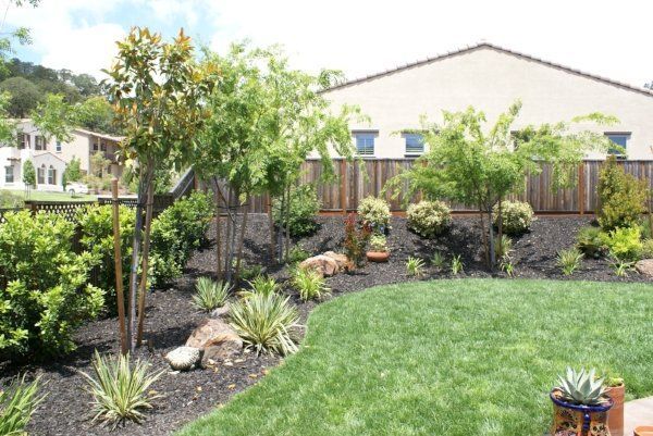 Backyard Landscaping Design by Turfworks, Inc. with a lush green lawn and a wooden fence