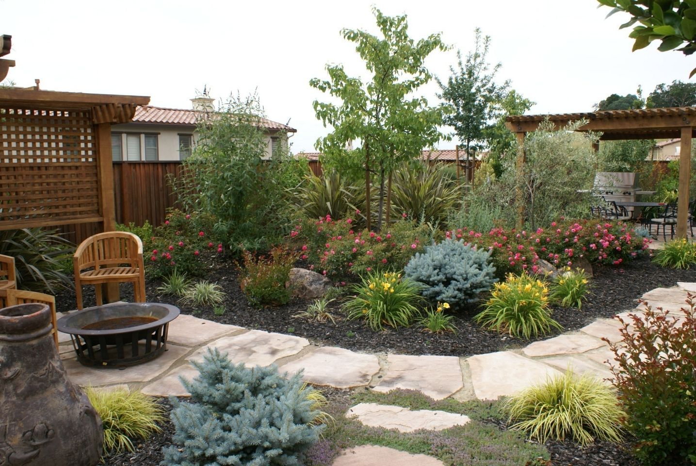 A landscape design in Davis, CA with a fire pit in the middle of the garden. 