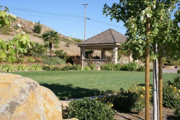 A landscape design in Davis, CA with a gazebo sits in the middle of a lush green field.