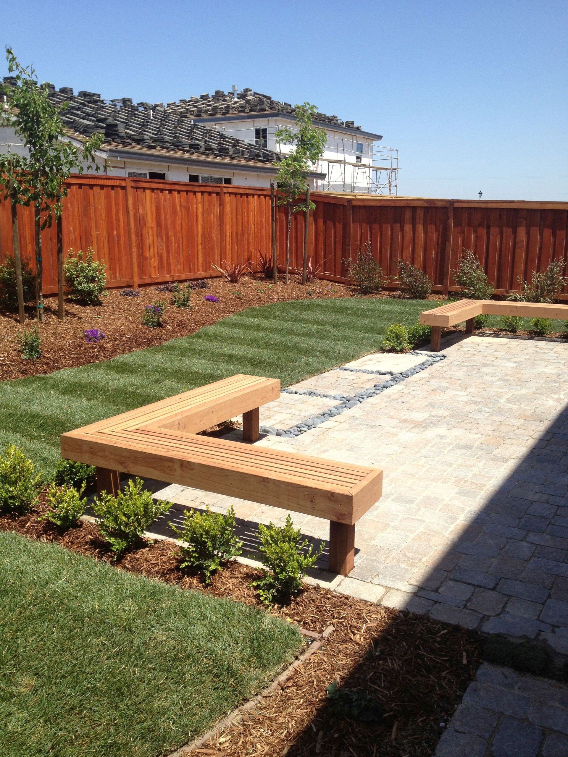 A wooden bench is sitting in the middle of a lush green yard landscape design in Davis, CA.