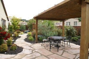 A patio with a table and chairs under a pergola | Landscape Design in Davis, CA