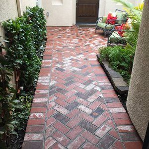 A paver walkway leading to a patio with chairs and plants | Landscape Design in Davis, CA