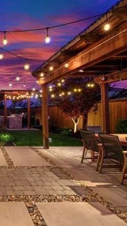 A pergola with table & chairs surrounded by outdoor lights by Turfworks Inc., the top landscape company in Vacaville, CA