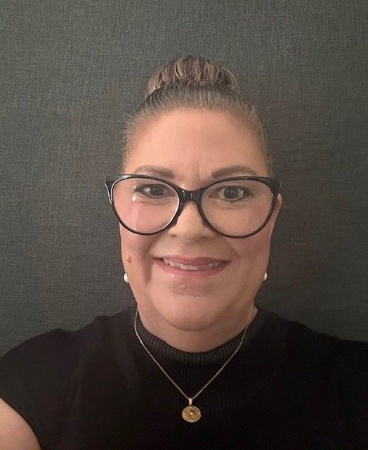 A woman in a pink shirt is smiling for the camera.