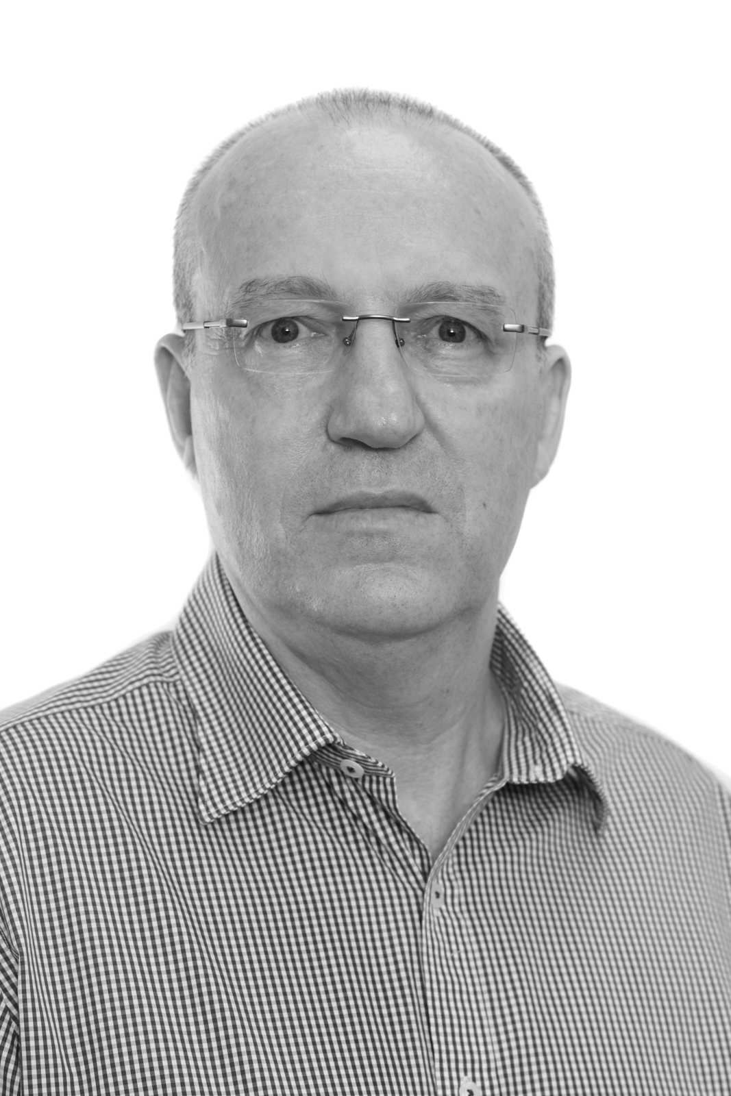 A black and white photo of a man wearing glasses and a plaid shirt.