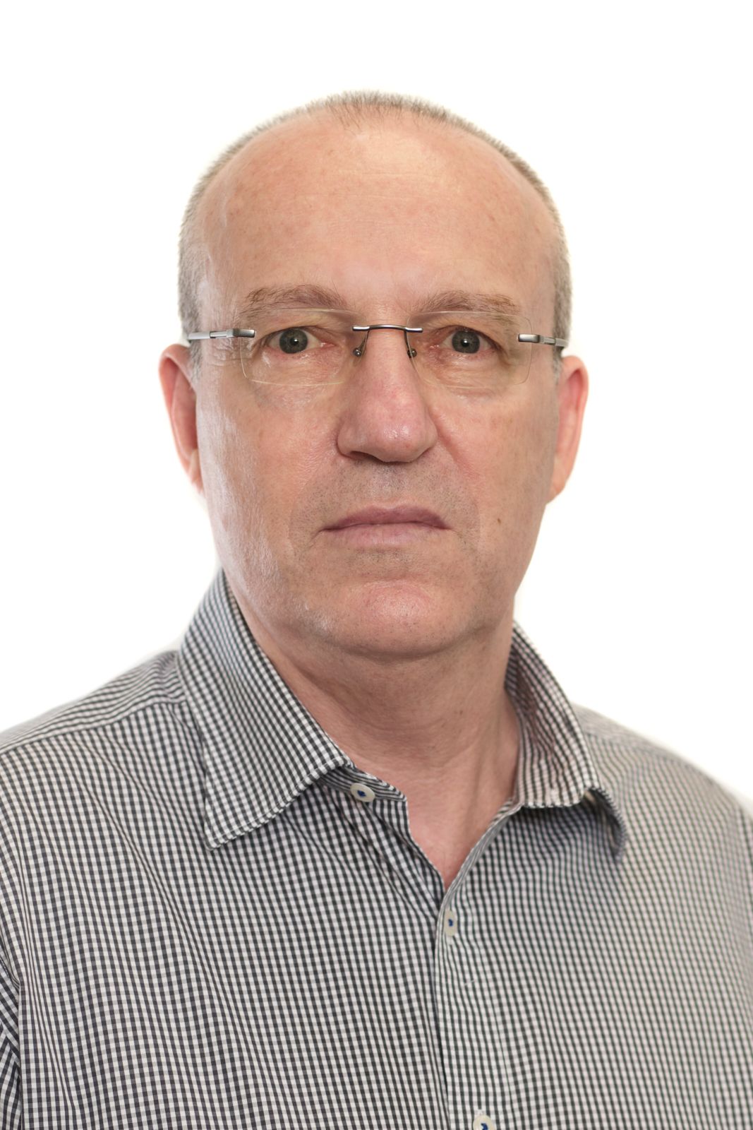 A man wearing glasses and a plaid shirt is looking at the camera.