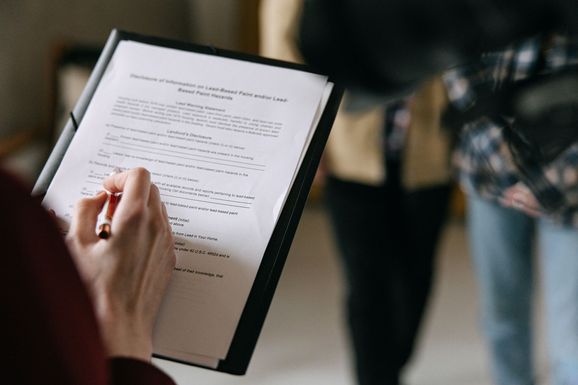 A person is holding a clipboard with a pen in their hand.