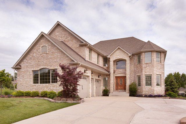 A large brick house with a large driveway in front of it