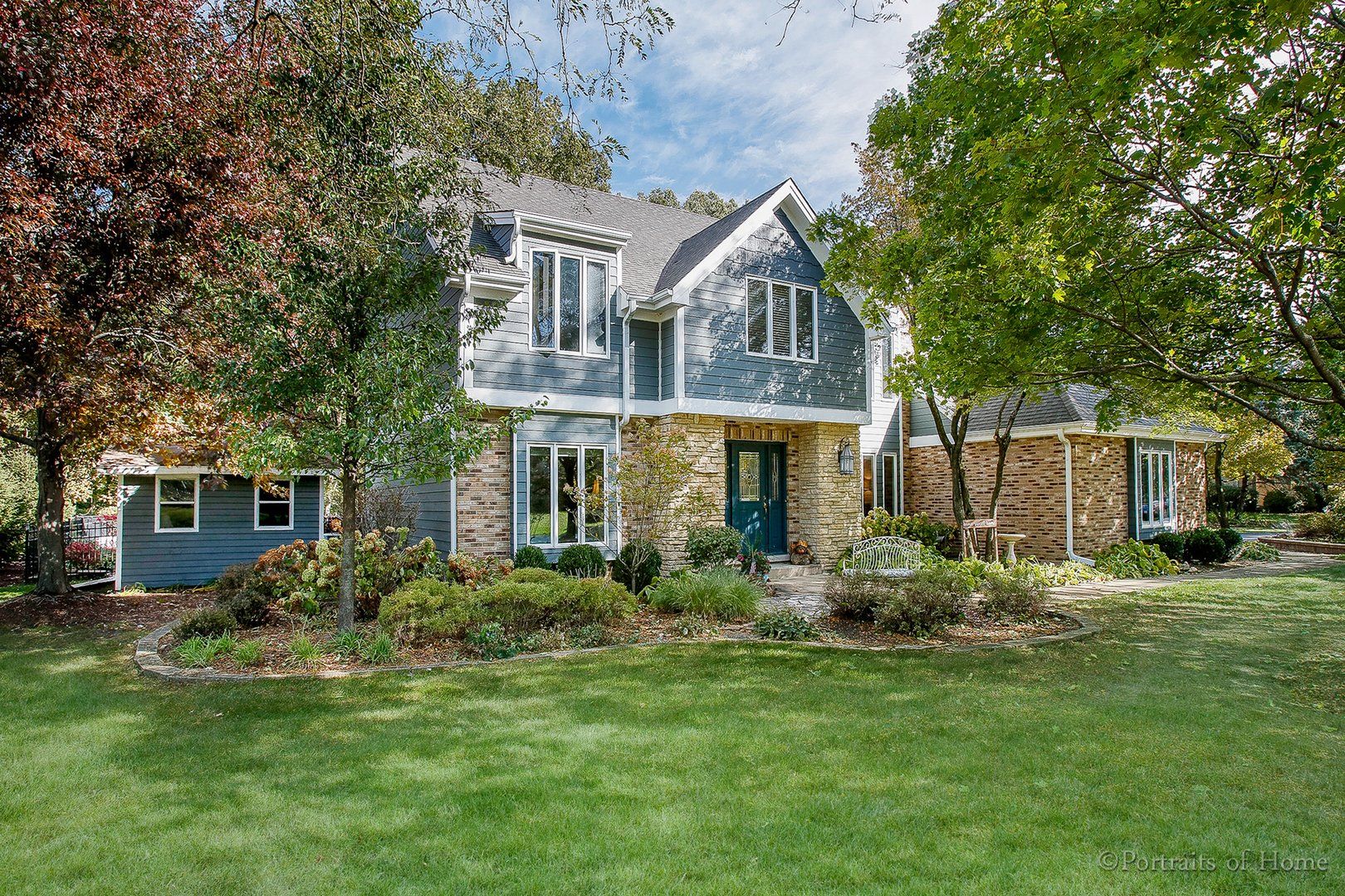 A large house with a lush green lawn and trees in front of it.