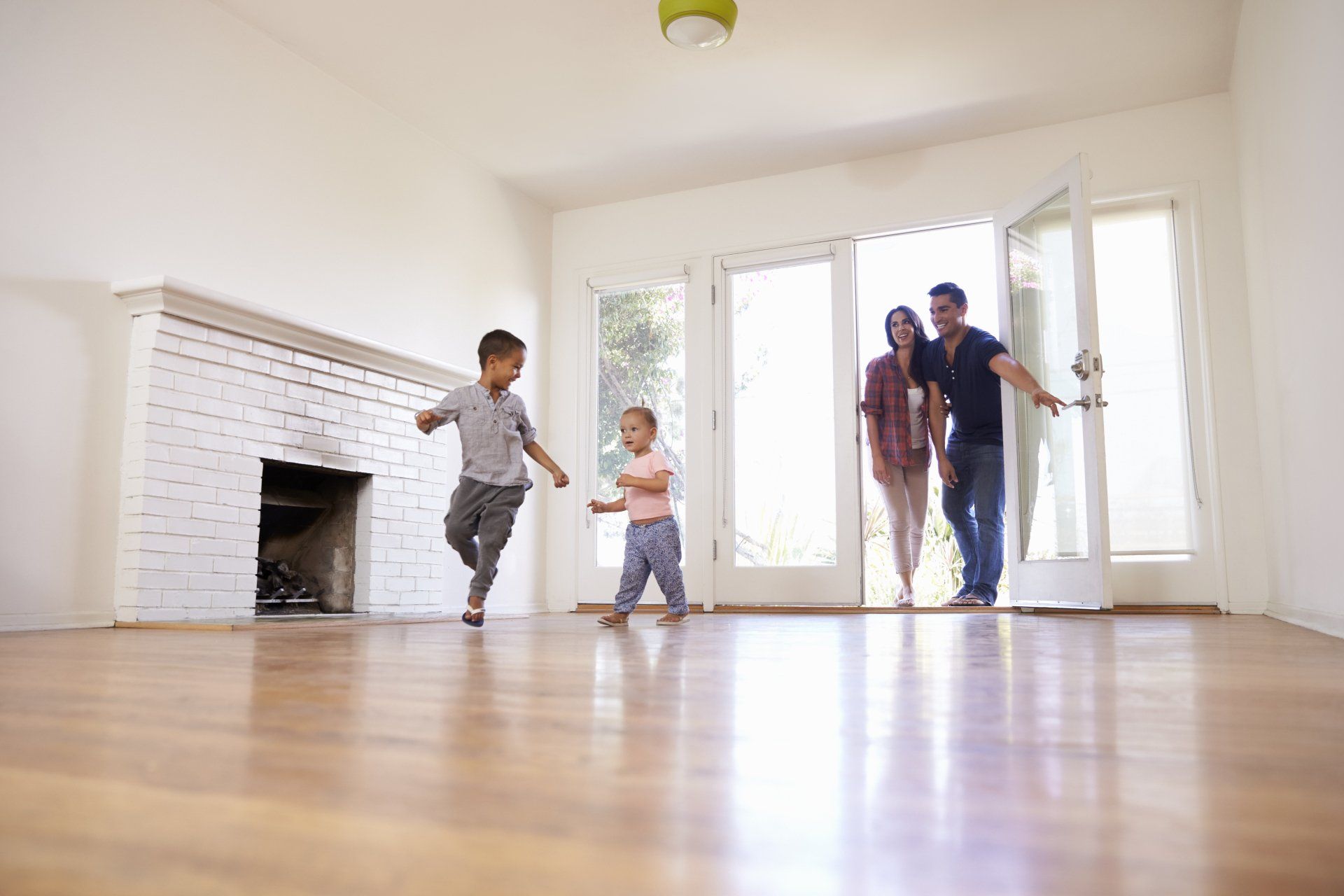 A family is standing in an empty living room in their new home.