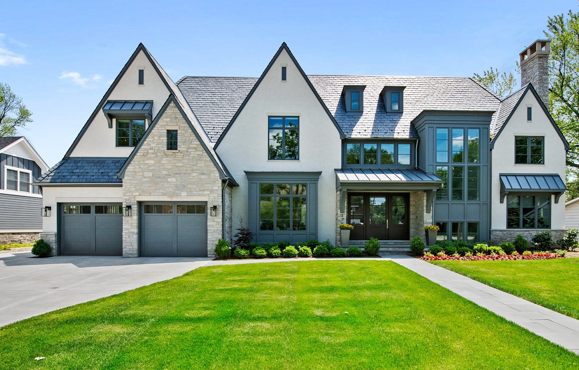 A large house with a lot of windows and a lush green lawn