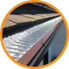 Gutter with a metal screen installed. The gutter is brown and against a brown shingle roof.