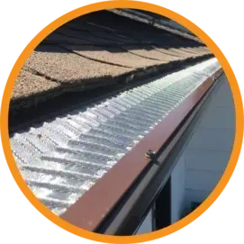 Gutter with a metal screen installed. The gutter is brown and against a brown shingle roof.