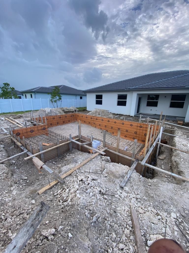 A swimming pool is being built in the backyard of a house.