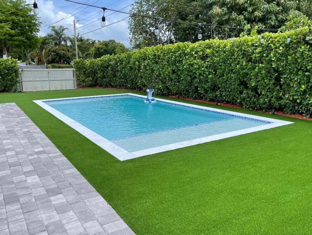 A large swimming pool is surrounded by a lush green lawn.