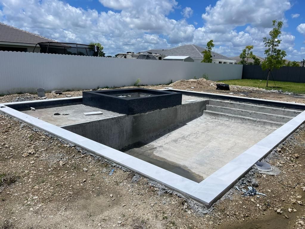 A large concrete pool is being built in a backyard