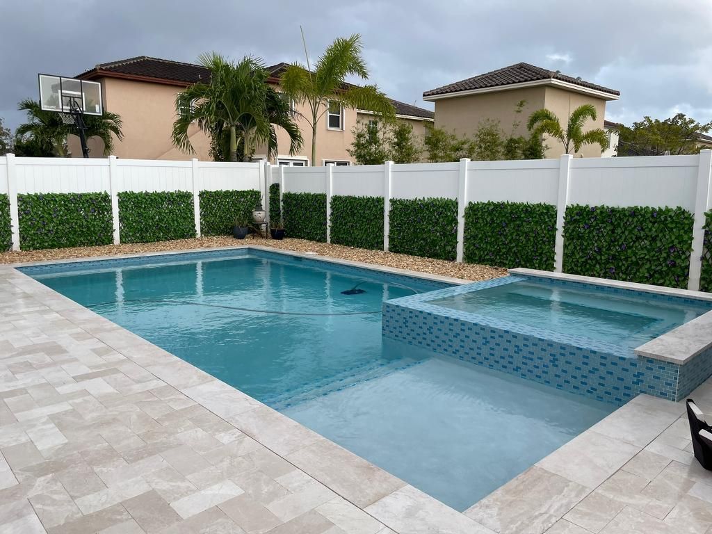 A large swimming pool with a white fence surrounding it