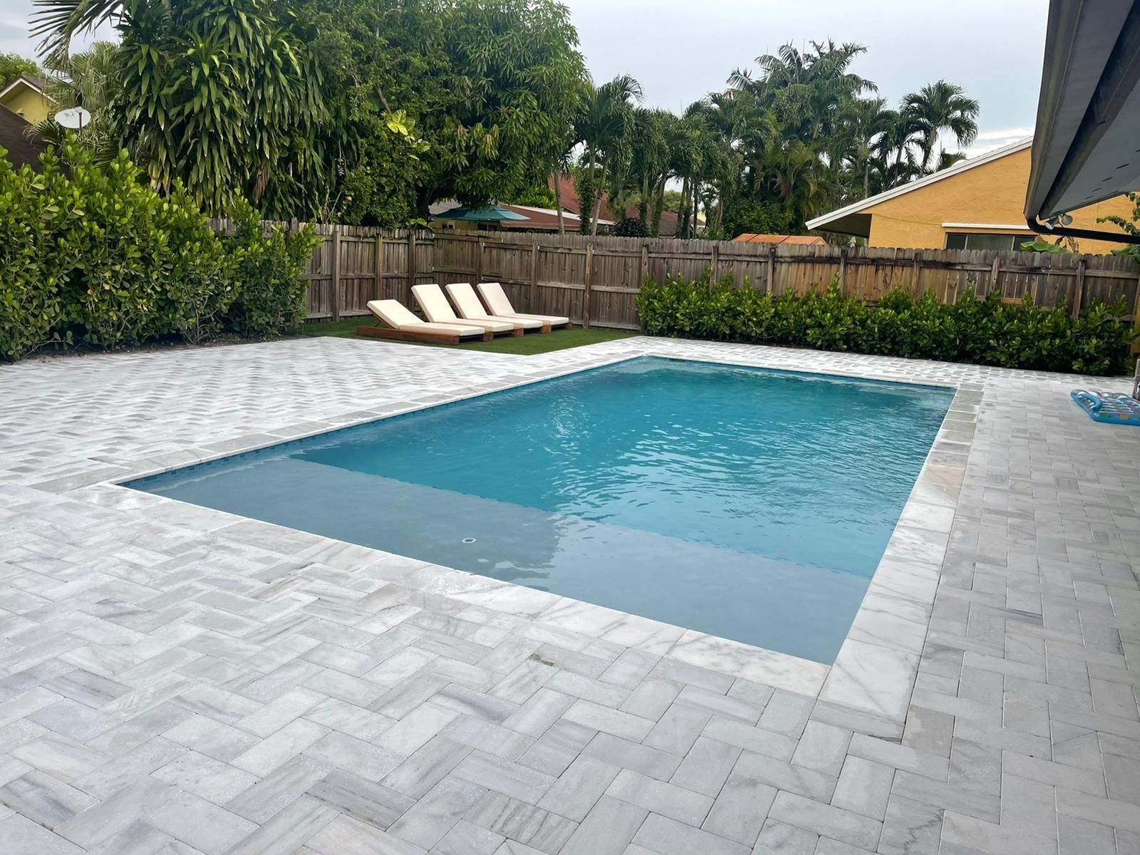 A large swimming pool is in the backyard of a house.