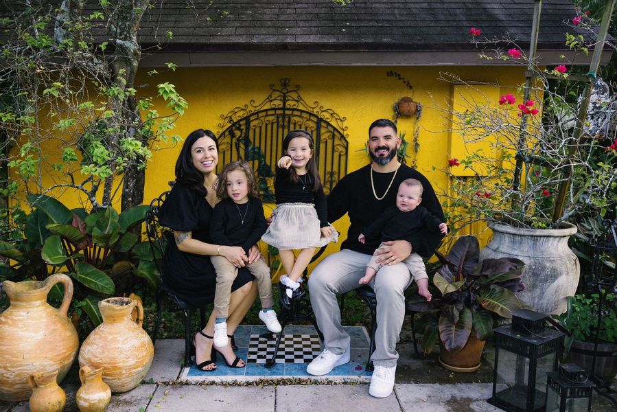 A family is posing for a picture in front of a yellow wall.